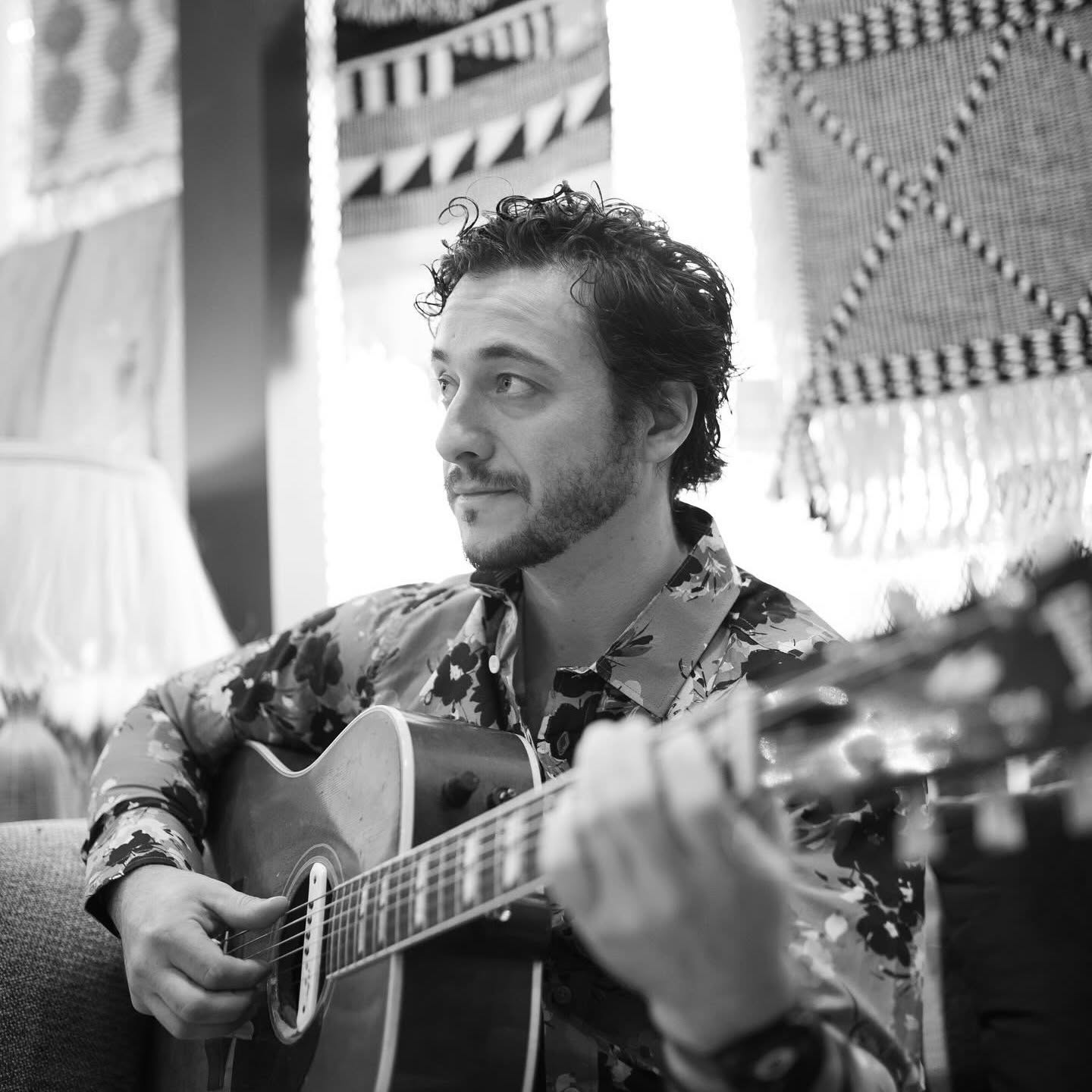 Black-and-white portrait of Nathan playing acoustic guitar
